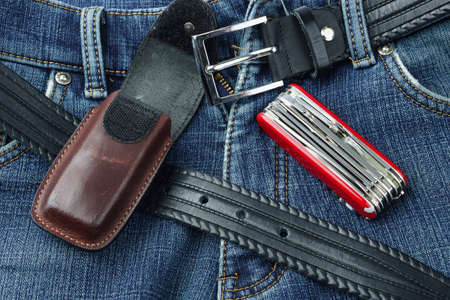 Detail of blue jeans with leather belt, penknife and caseの写真素材
