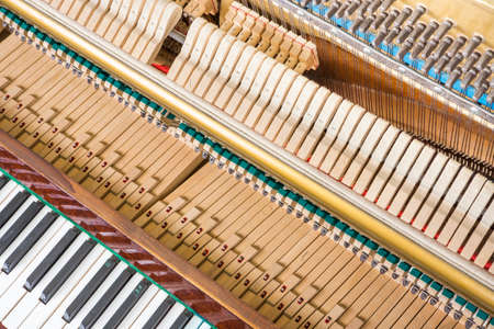 Action mechanics close up inside of an upright piano. Pattern of keys, shanks, hammers and strings.の写真素材