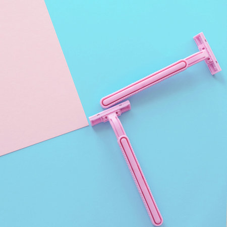 Square Composition with Two Female Razors On The Pastel Background Light Pink and Blue Colors...