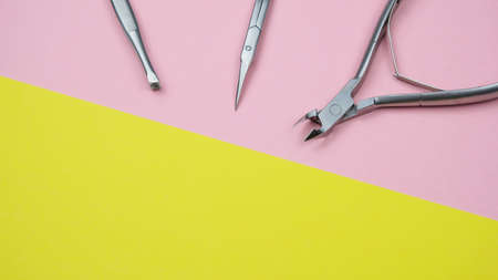 Composition With Manicure Tools. Scissors For Nails, Tweezers, Forceps On The Geometric Pastel Pink And Yellow Colors Background Minimal Style Flat Lay Copy Space Long Bannerの写真素材