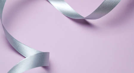 Abstract Gentle Pink Background With Silver Ribbon Curls. Minimal Style Flat Lay Copy Spaceの写真素材