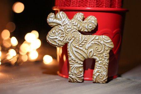 Gingerbread cookie and Christmas decorations on a table. Festive blurred lights, red candle and...