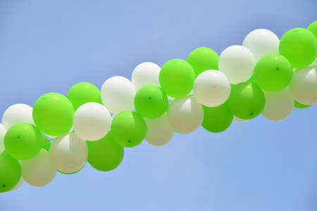 Strings Of Green And White Balloons Against Clear Blue Skyの写真素材