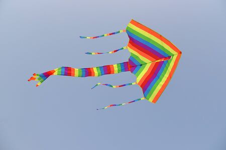 Colorful Kite With long Tails Flying Against Clear Blue Skyの写真素材
