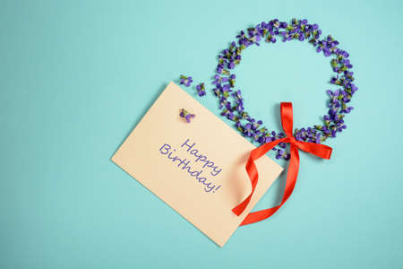 Beautiful violets in circle form on light blue background. Happy Birthday greeting cardの写真素材