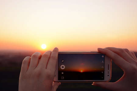 Photographing the sunset with smartphone in the hands closeupの写真素材