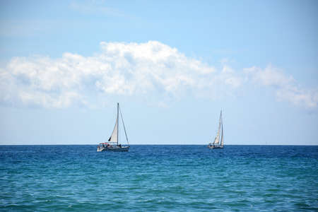 White sailboat in the amazing Mediterranean sea, beautiful cumulus clouds. Travel timeの写真素材