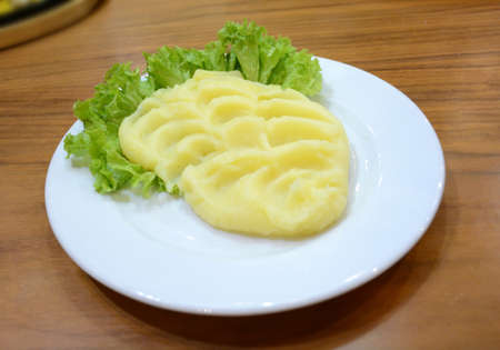 Mashed potatoes and lettuce leaves on a white plateの写真素材