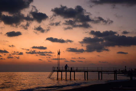 Summer romantic background on sunset. Couple of lovers on the pierの写真素材