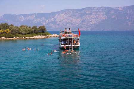 Turkey, Aegean island - June 28, 2019. People jump from sailing yacht and swim in open sea in Aegean islands on mountains background, Turkeyのeditorial素材