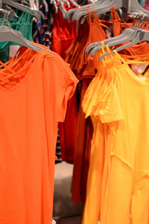 Clothes on hangers in store. Bright dresses hang on clothing rack. Shopping time concept