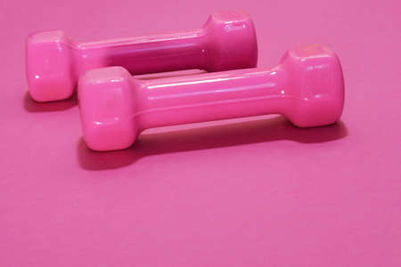 Pink dumbbells isolated on pink background with copy space. Womens fitness equipmentの写真素材
