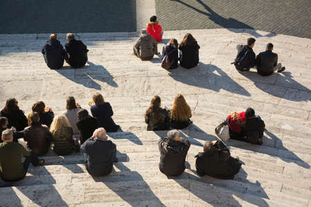Crowd of people sitting on city street stairs back behind top view at sunny day. Concept of rest and meet in the cityの写真素材