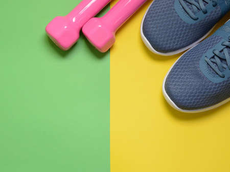Sport sneakers and dumbbells on yellow green background with copy space for text. Sport objects background. Sports conceptの写真素材