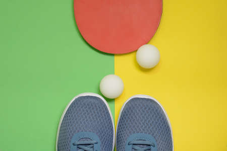 Table tennis racket, balls and sport sneakers on yellow green backgroundの写真素材