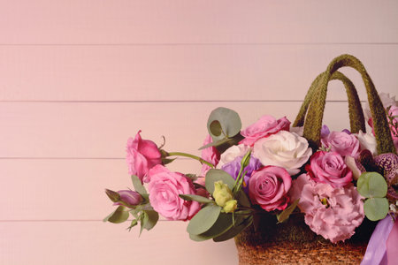 Bouquet of pink roses in basket on pink wooden background closeup. Roses and eustoma flowers greeting card, floristics, wedding, flower shop, holidayの写真素材