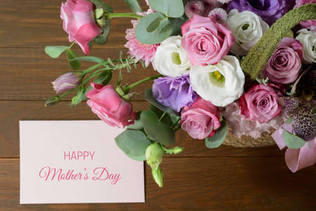 Mothers day card. Bouquet of pink roses in basket on wooden background closeupの写真素材