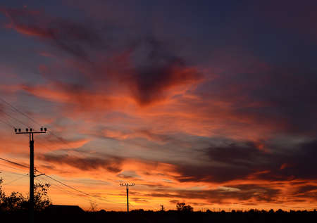 Bright red sunset. Orange yellow red sky background and power lines. Palette of sunset colorsの写真素材