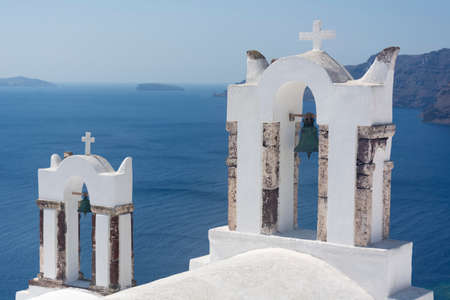 Santorini bell tower of white church in Oia with sea view and volcano, Greece landmark. island architecture.の写真素材