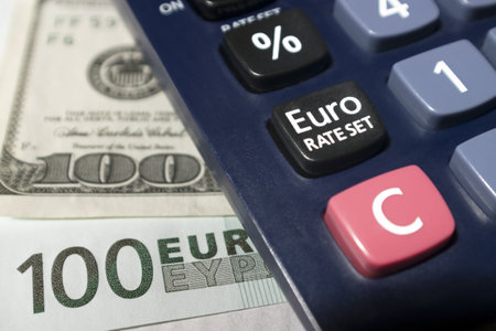 Part-view of a calculator, Euro rate set button with euro and dollar banknotes as backgroundの写真素材