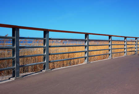 Perspective view of metal handrail, clear blue sky and walkwayの写真素材