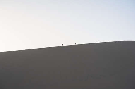 Two hikers climb on the sand dunes, Dunhuang, Gansu of Chinaの写真素材