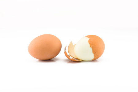 One egg and one boiled split egg on the white background