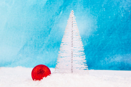 New Year tree completely covered with snow in snow and bright red New Year ornament next to the Christmas pine tree shootの写真素材
