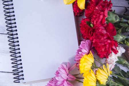 flowers and notebook on wooden backgrodundの写真素材