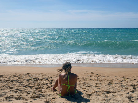 Female in bikini sitting on sunny beach