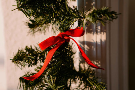 Christmas tree decorated with red ribbon and bow, close-up.