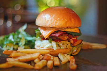 Cheese burger - American cheese burger with Golden French fries on wooden plate