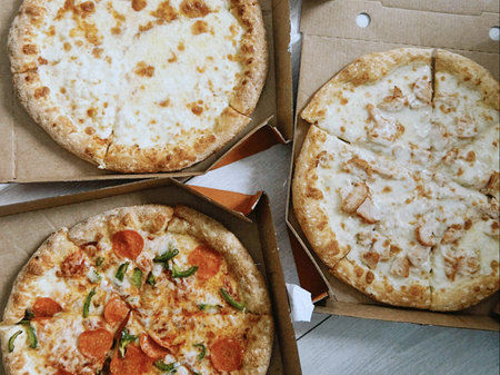 Pizza with mozzarella cheese, tomato and basil in cardboard boxes