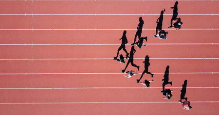 Athletes running on a track and field, shot from above