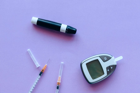 Glucose meter and syringe on purple background. Diabetes concept