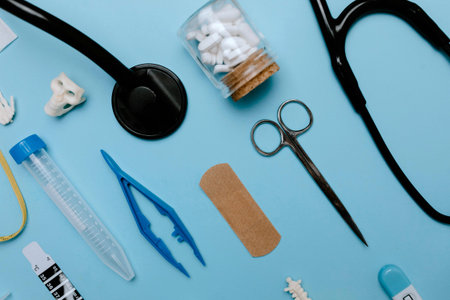 Medical equipment on blue background. Stethoscope, bandage, pills, plaster, scissors.