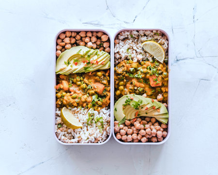 Healthy lunch box with chickpeas curry, rice, avocado and chickpeas. Vegetarian food.