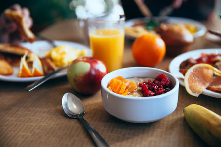 Healthy breakfast with oatmeal, fruits and orange juice on wooden table