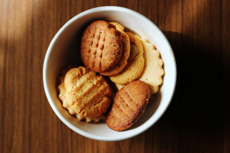 Cookies in a white bowl on a wooden table, top view