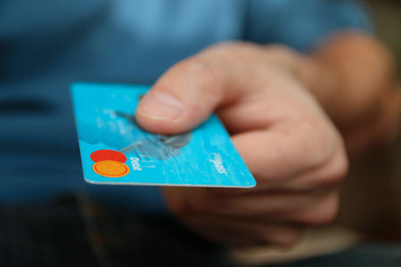 A man holds a credit card in his hand. Selective focus.