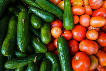Tomatoes and cucumbers on the counter of a farmers market.