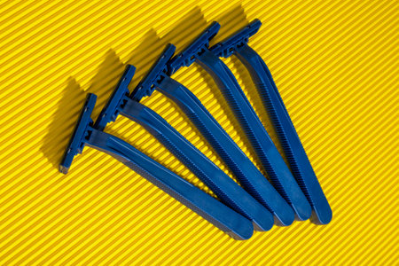 Set of blue disposable razor blades on yellow background. Top view.
