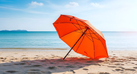 Orange umbrella on the beach with blue sea and sky background. Copy space.