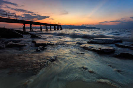 View of a beach with a jetty at sunsetの写真素材