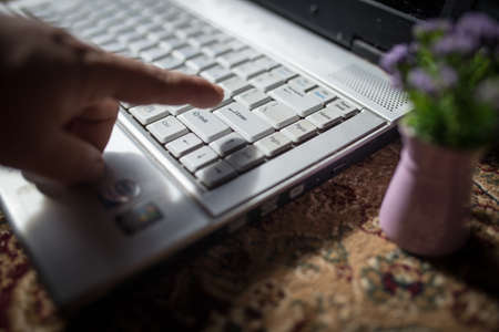 man finger about to press on enter key on laptopの写真素材