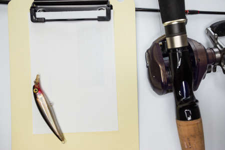 fishing rod and fishing lure on blank paper noteの写真素材