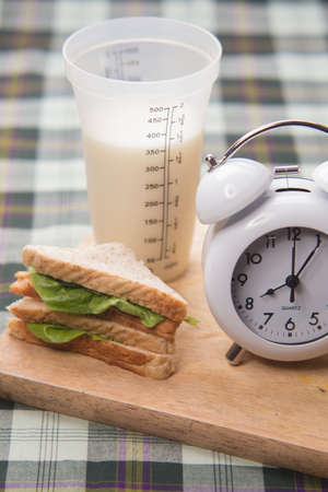 sandwich and glass of fresh milk on cutting boardの写真素材