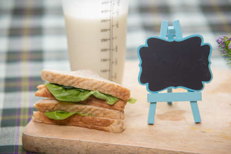 sandwich and glass of fresh milk on cutting boardの写真素材