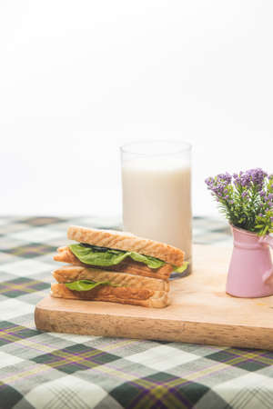 sandwich and glass of fresh milk on cutting boardの写真素材
