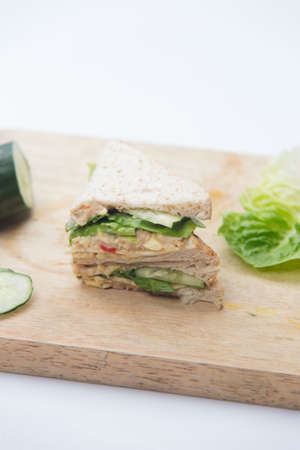 sandwich, cucumber and salad on cutting boardの写真素材